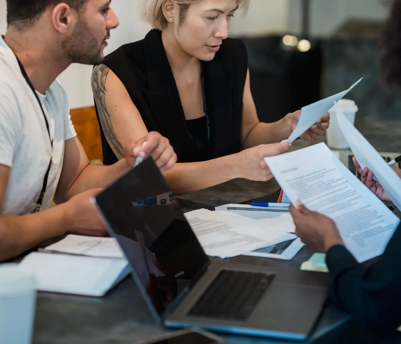 A collaborative office team reviewing printed documents and notes together.